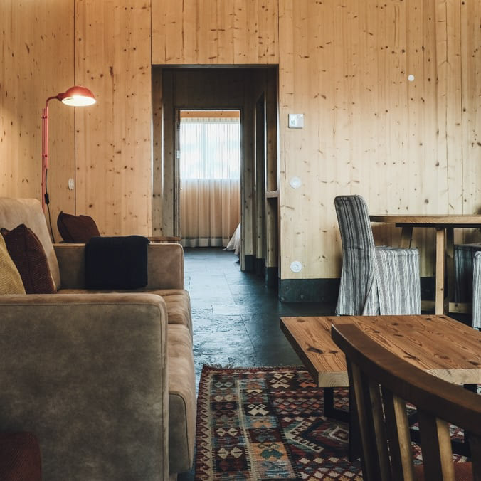 Interior de um bungalow do FeelViana, com as paredes em madeira natural. Dispõe de uma sala espaçosa e de um corredor. 