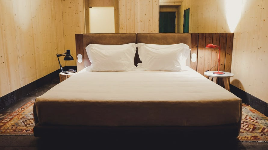 Quarto do Hotel FeelViana, com as paredes e acabamentos em madeira natural. Dispõe de uma confortável cama king size. 