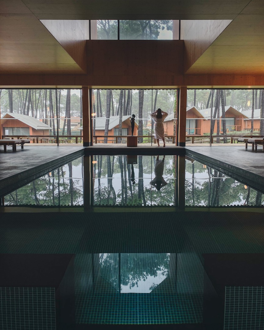 Momento de relaxamento na piscina interior aquecida do FeelViana Spa, com vista para os bungalows do Hotel e o pinhal.